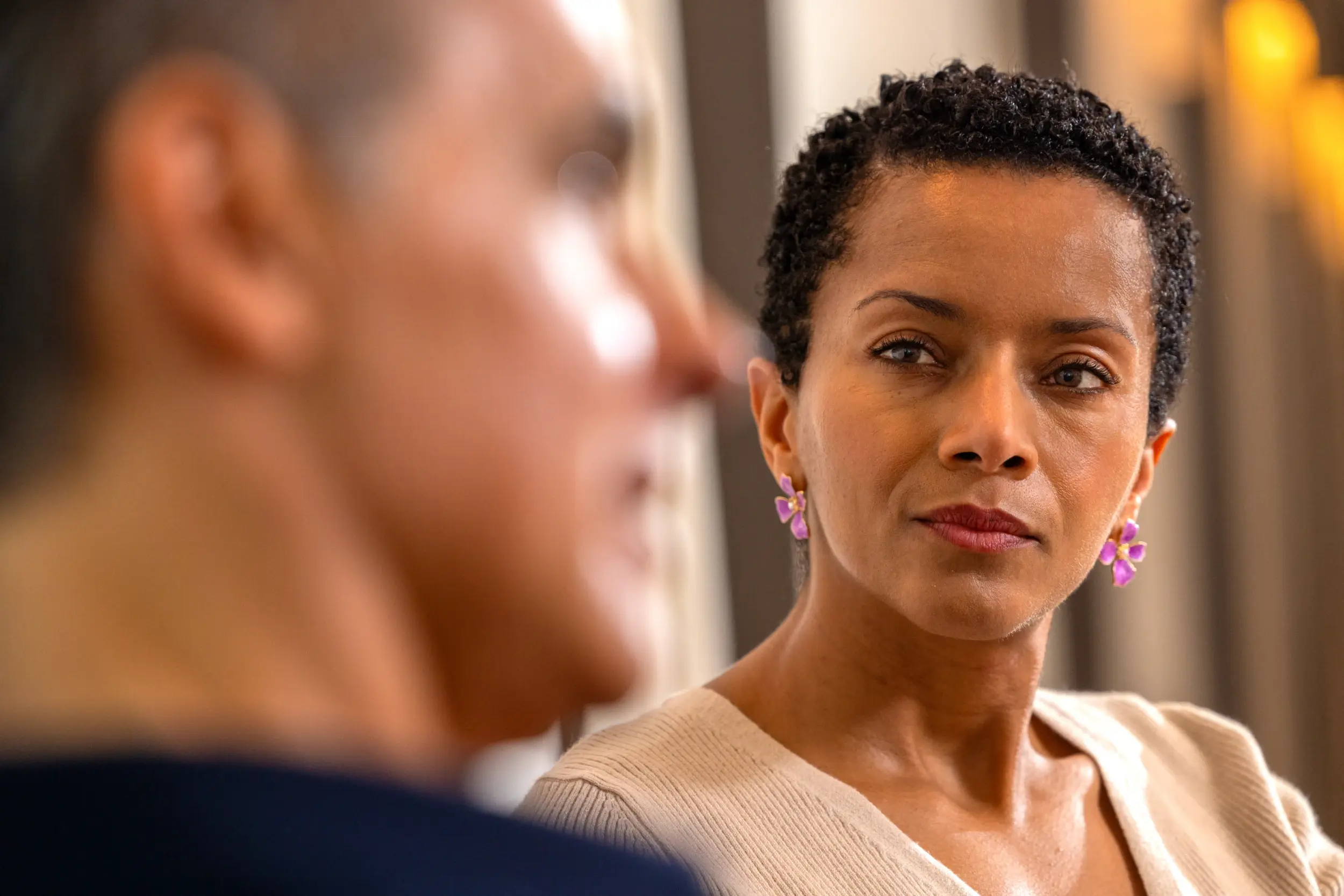 Woman in a white sweater looking attentively at a man during a conversation.